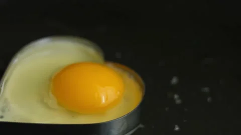 Cooking fried egg in the shape of heart in a frying pan. Cooking a surprise Stock Footage 150499156