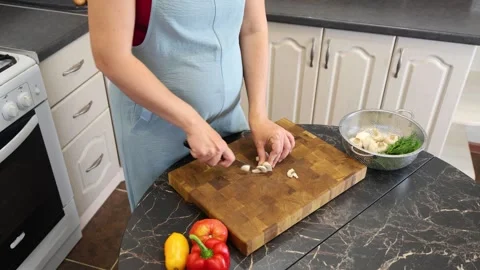 Cooking fried eggs with vegetables at home. A woman chops vegetables on a wooden Stock Footage 317542998