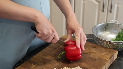 Cooking fried eggs with vegetables at home. A woman chops vegetables on a wooden Stock Footage 317543287