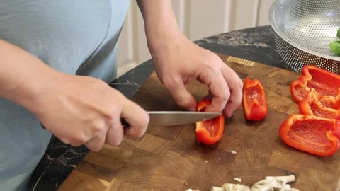Cooking fried eggs with vegetables at home. A woman chops vegetables on a wooden Stock Footage 317543453