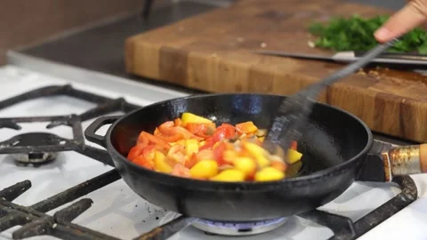 Cooking fried eggs with vegetables at home. A girl fries fried eggs with vegetab Stock Footage 317544031