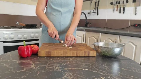 Cooking fried eggs with vegetables at home. A woman chops vegetables on a wooden Stock Footage 317544457