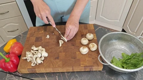 Cooking fried eggs with vegetables at home. A woman chops vegetables on a wooden Stock Footage 317544462