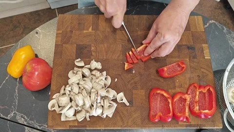 Cooking fried eggs with vegetables at home. A woman chops vegetables on a wooden Stock Footage 317544695