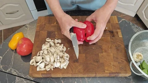 Cooking fried eggs with vegetables at home. A woman chops vegetables on a wooden Stock Footage 317544702