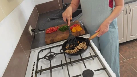Cooking fried eggs with vegetables at home. A girl fries fried eggs with vegetab Stock Footage 317545139