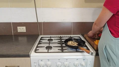 Cooking fried eggs with vegetables at home. A girl fries fried eggs with vegetab Stock Footage 317545164
