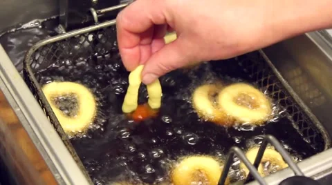 Cooking fried oil. Kitchen. Hand introduces doughnuts in fryer. Stock Footage 65257697