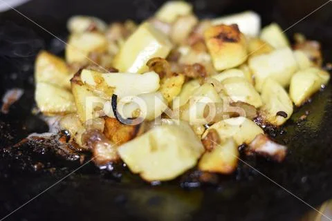 Cooking fried potatoes in outdoor conditions on fire. Fire fried potatoes Stock Photos