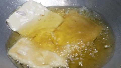 Cooking fried tempeh coated with wheat flour in hot oil in a frying pan Stock Footage 302944032