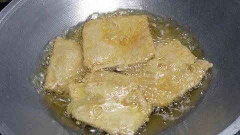 Cooking fried tempeh coated with wheat flour in hot oil in a frying pan Stock Footage 302944180
