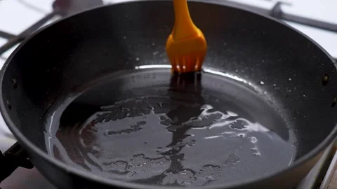 Cooking on frying pan process. Man hands applying sunflower oil with silico.. Stock Footage 272156193