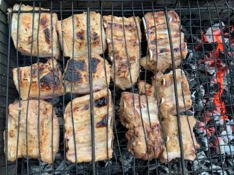 Cooking grilled steak on the grill. Burning coals on the grill, pork skewers  Stock Photos