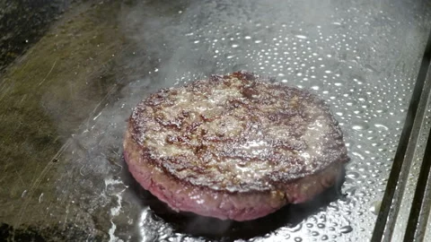 Cooking hamburger. Chef peppering over beef or pork cutlet grilling on grid. 4K Stock Footage 98028602