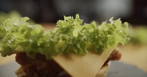 Cooking hamburger. Close-up of chef hands puts half bun on ready-made burger. 4K Stock Footage 116178581