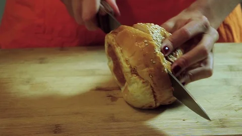 Cooking hamburger. Hands cutting bread rolls with sesame seeds on the parts. HD 動画素材 71789310