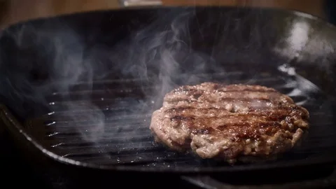 Cooking hamburger. One beef patty for burger is being fried in a broiler pan. 4K Stock Footage 79847399