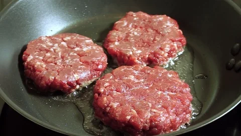 Cooking hamburger. Three beef cutlets for burgers are fried in a frying pan. HD Stock Footage 70660347