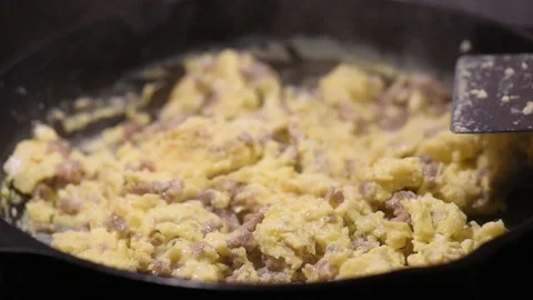 Cooking handheld serving sausage eggs onto plate with bagel Stock Footage 93969884