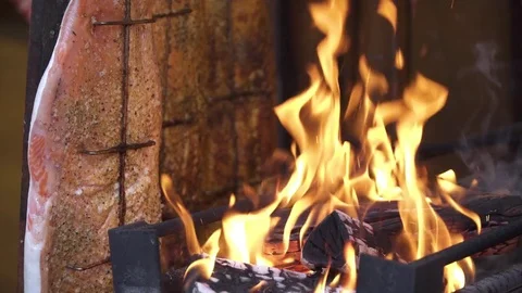 Cooking hang fish grill with coarse salt. Wood fire and flame close up. Stock Footage