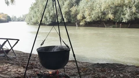 Cooking on a hanging cauldron over a fire, on the river bank 스톡 동영상 257046759