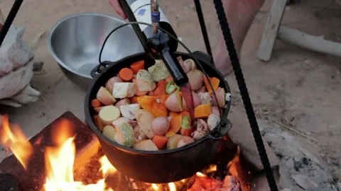 Cooking a hearty stew over an open fire in the outdoors 動画素材 320198752