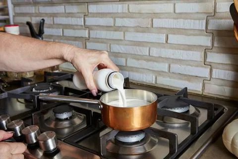 Cooking at home in the kitchen using a recipe from the Internet. woman pours  Stock Photos