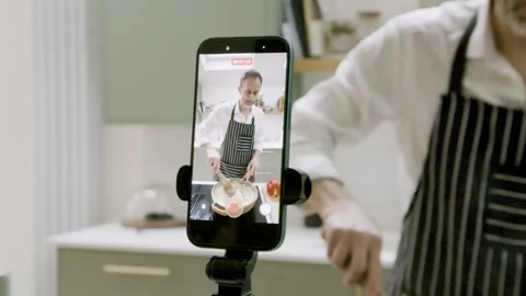 Cooking Influencer Filming Cooking Tutorial on Smartphone in Modern Kitchen Stock Footage 328761270