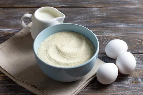 Cooking ingredients featuring a blue ceramic bowl filled with semolina, thr.. Stock Photos