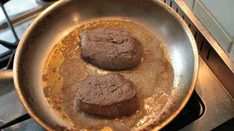 Cooking in a kitchen steaks are baked in a frying pan Stock Footage