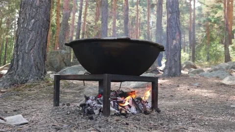 Cooking in large cauldron on a fire outdoor in the forest Stock Footage 115083213