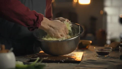 A cooking masters hands gently crush fresh organic cabbage in bowls releasin Stock Footage 331311766