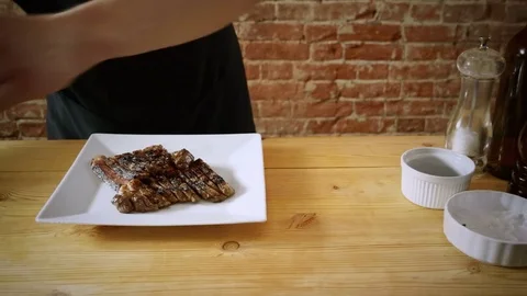 Cooking meat. A chef decorating a dish of fillet beef steak on a white plate. 4K Video stock 84714437