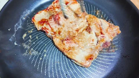 Cooking meat in a frying pan over a hot plate Stock-Footage 338086278