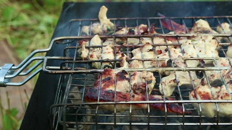 Cooking meat over an open fire. Smoke and flames from smoldering charcoal.  Stock Footage 69009980