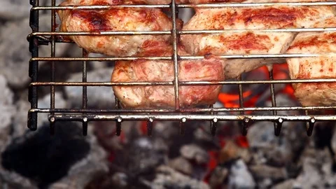 Cooking meat over an open fire. Smoke and flames from smoldering charcoal Stock Footage