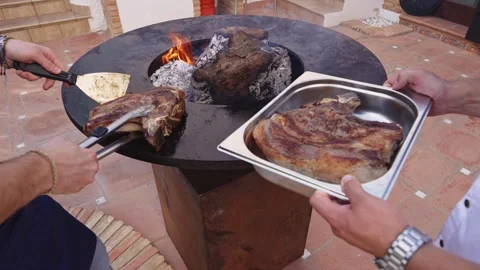 Cooking meat over open fire at outdoor grill in backyard during sunny afternoon Stock Footage 337105859