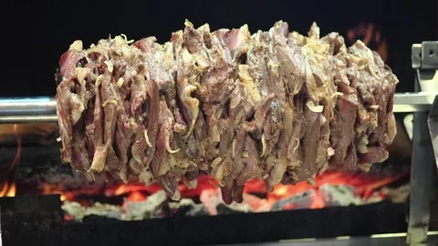 Cooking meat on a spit over hot coals in an open fire Stock Footage 334517284