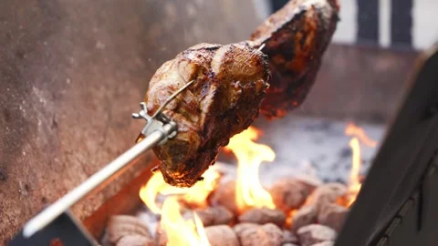 Cooking meat on a spit over open flames at an outdoor grill 스톡 동영상 332053869