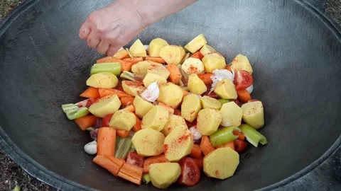 Cooking meat with vegetables over a fire Stock Footage 334939981