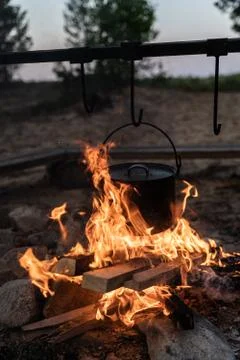 Cooking in a metal pot on a fire while camping, close up of organ in flames Stock Photos