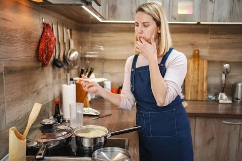 Cooking in a modern kitchen while tasting a delicious homemade dish Stock Photos