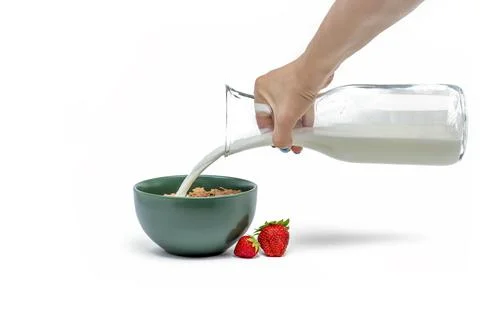 Cooking muesli, isolate on white background Woman pours milk from a jug into  Stock Photos