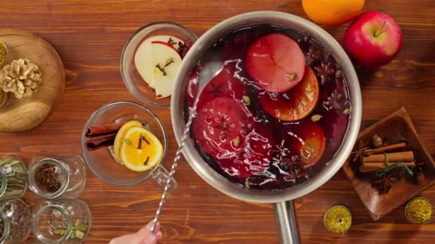 Cooking mulled wine top view, gluhwein recipe. Mixing red hot wine with apples Video stock 165768152