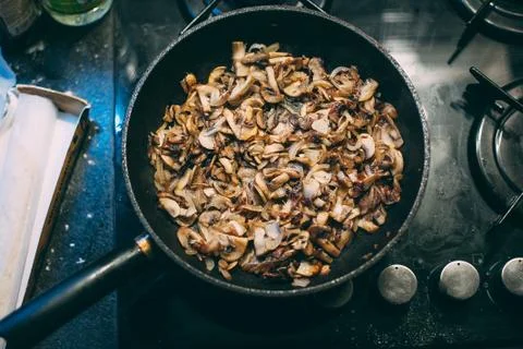 Cooking mushrooms in a pan. Stirring with a spatula. Stock Photos