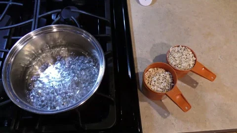Cooking Oatmeal adding Oatmeal to boliing water Stock Footage 329448386