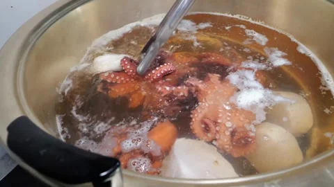 Cooking octopus and squid in a large pot of boiling water with vegetables Stock Footage 345510441