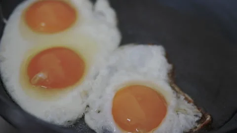 Cooking an omelet in a frying pan, appetizing chicken eggs without shells Stock Footage 142386101