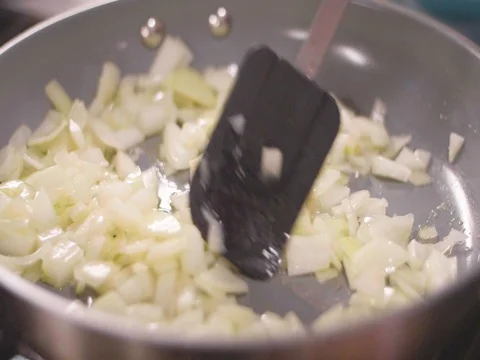 Cooking onions in frying pan in slow motion Stock Footage