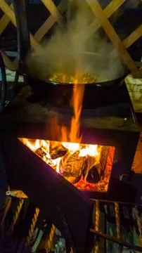 Cooking on an open fire in the cauldron at night. Stock Photos